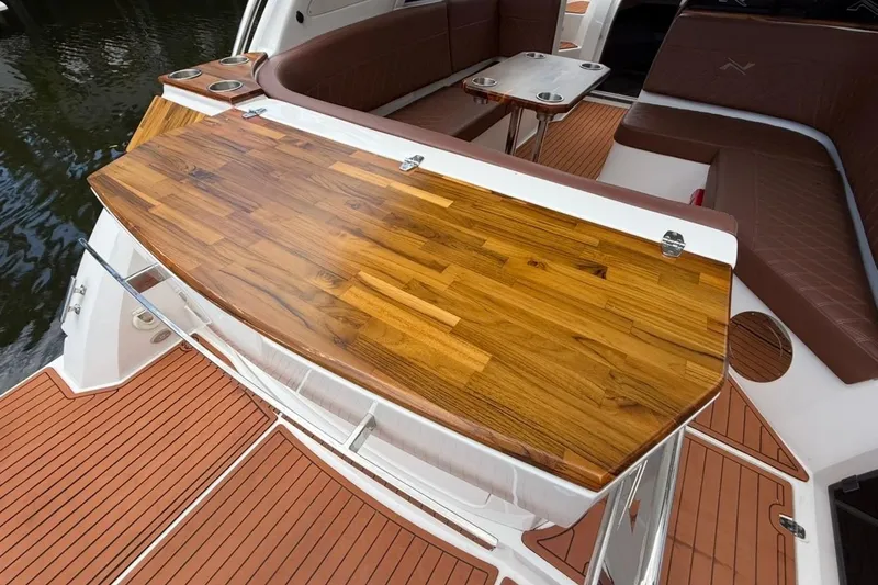 Slide: The Image of 2025 NX Boats 340 Sport Coupe interior with wooden deck and seating area. - 24