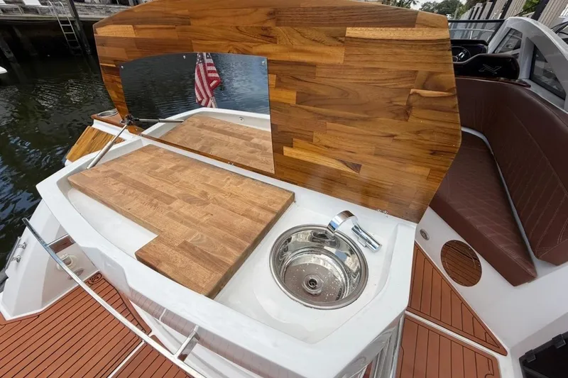 Slide: The Image of 2025 NX Boats 340 Sport Coupe with wooden deck and built-in sink. - 25