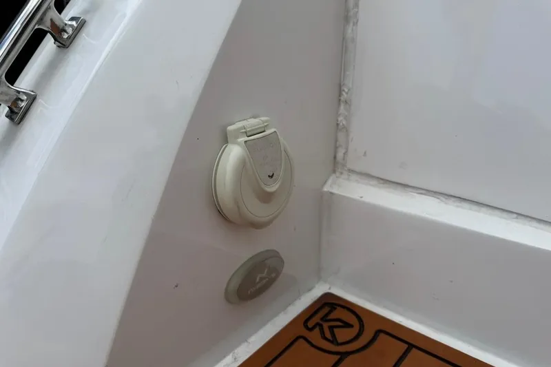 Slide: The Image of 2025 NX Boats 340 Sport Coupe interior detail with electrical outlet and teak flooring. - 27