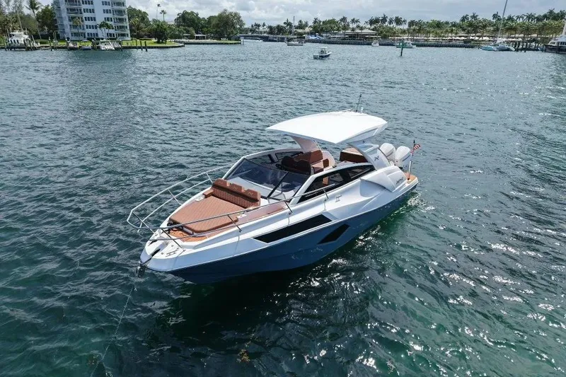 Slide: The Image of 2025 NX Boats 340 Sport Coupe cruising on a sunny day in a scenic waterway. - 3