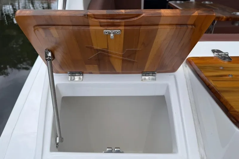 Slide: The Image of Open storage compartment on 2025 NX Boats 340 Sport Coupe with wooden lid. - 30