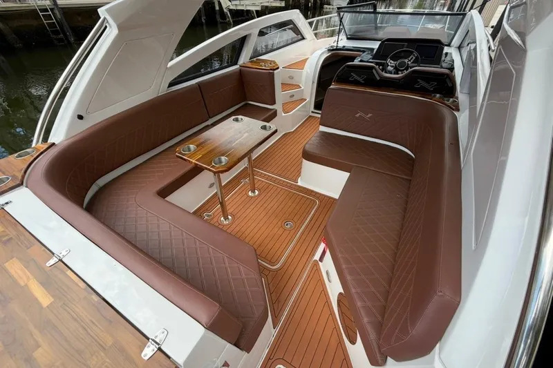 Slide: The Image of Luxurious interior of 2025 NX Boats 340 Sport Coupe with brown leather seating and wooden flooring. - 34