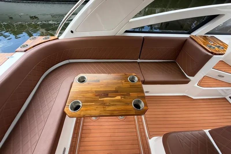 Slide: The Image of Luxurious seating area on 2025 NX Boats 340 Sport Coupe with wooden table and cup holders. - 35