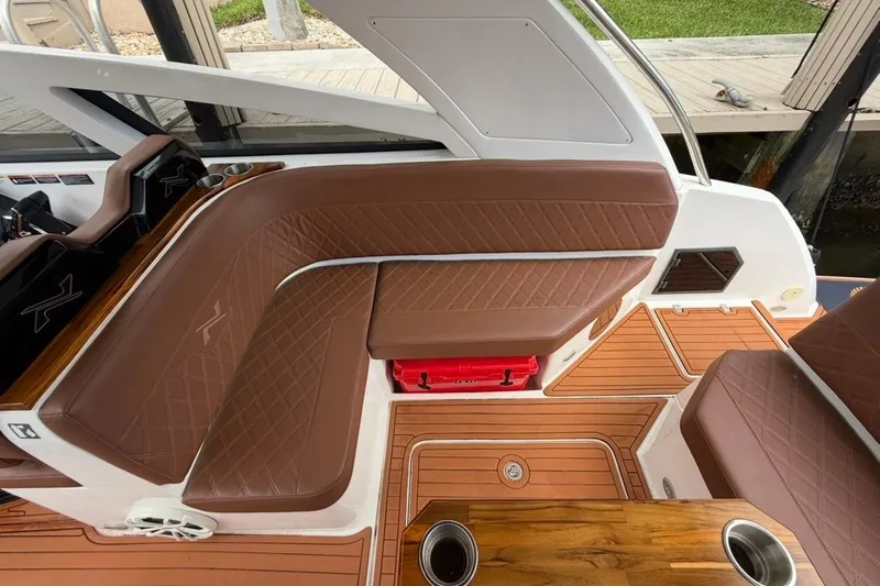 Slide: The Image of Interior of 2025 NX Boats 340 Sport Coupe with brown leather seating and wood flooring. - 36