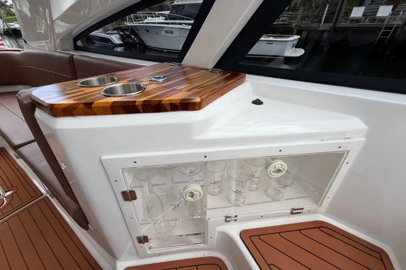 Slide: The Image of Interior of 2025 NX Boats 340 Sport Coupe with wooden countertop and glass storage. - 38