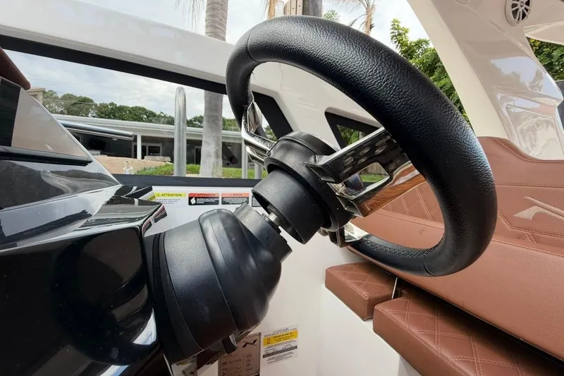 Slide: The Image of Steering wheel of 2025 NX Boats 340 Sport Coupe, featuring sleek design and leather seating. - 44