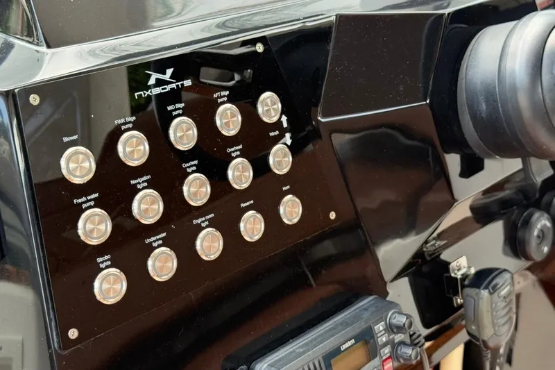 Slide: The Image of Control panel of 2025 NX Boats 340 Sport Coupe with labeled buttons and switches. - 52