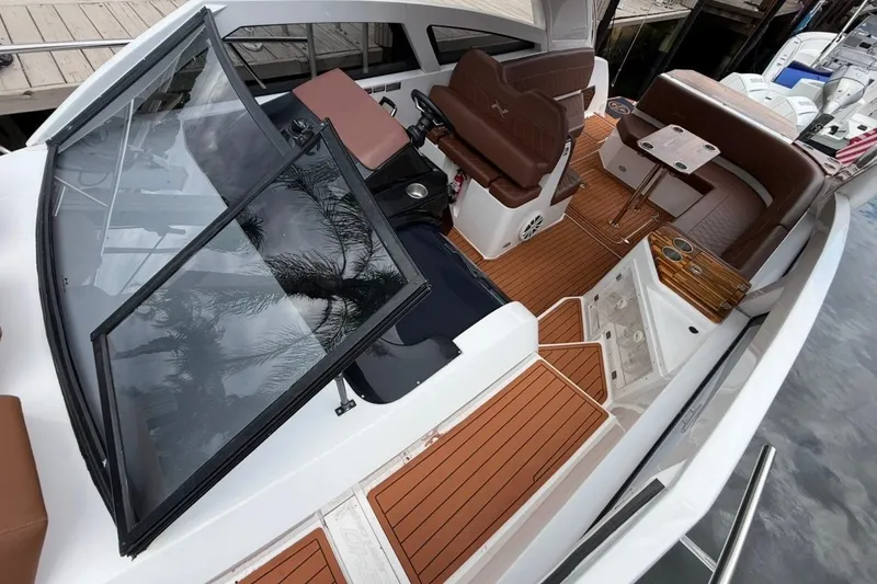 Slide: The Image of 2025 NX Boats 340 Sport Coupe interior with brown seating and wooden flooring. - 57