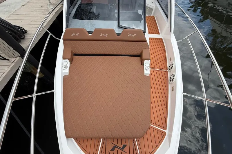 Slide: The Image of 2025 NX Boats 340 Sport Coupe with luxurious brown seating and teak deck details. - 58