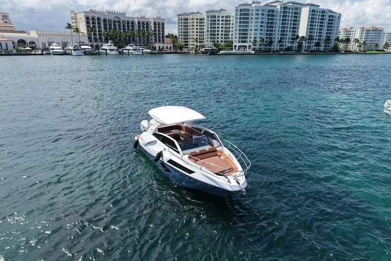 Slide: The Image of 2025 NX Boats 340 Sport Coupe on serene water with luxury buildings in the background. - 6