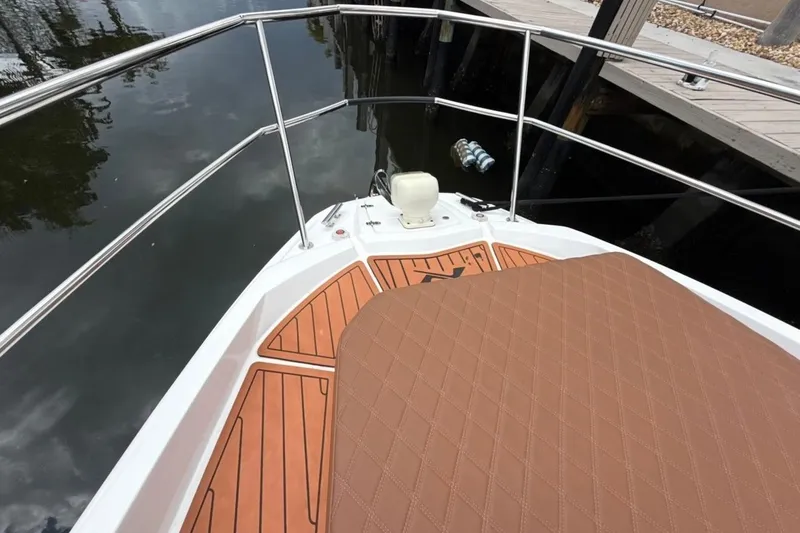 Slide: The Image of Bow view of 2025 NX Boats 340 Sport Coupe with teak decking and cushioned seating. - 60