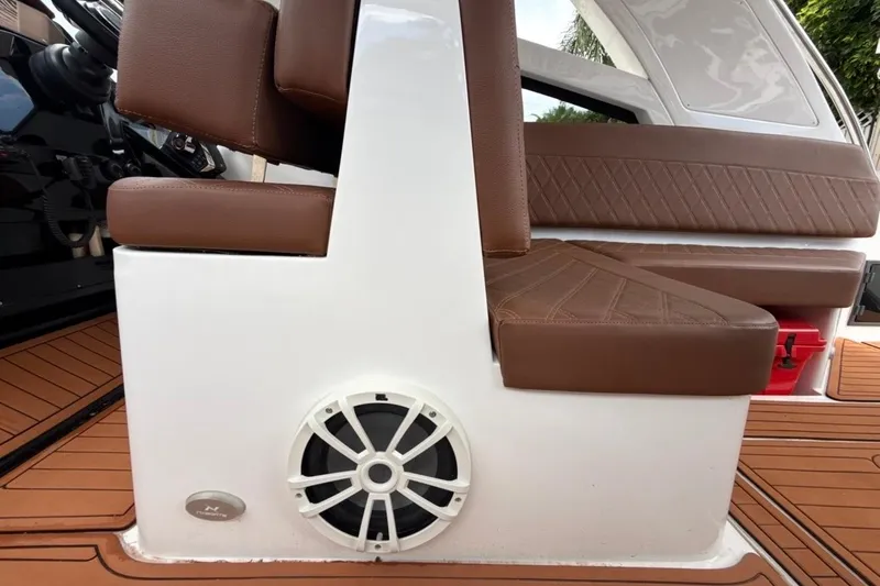 Slide: The Image of 2025 NX Boats 340 Sport Coupe interior with brown leather seating and speaker system. - 67