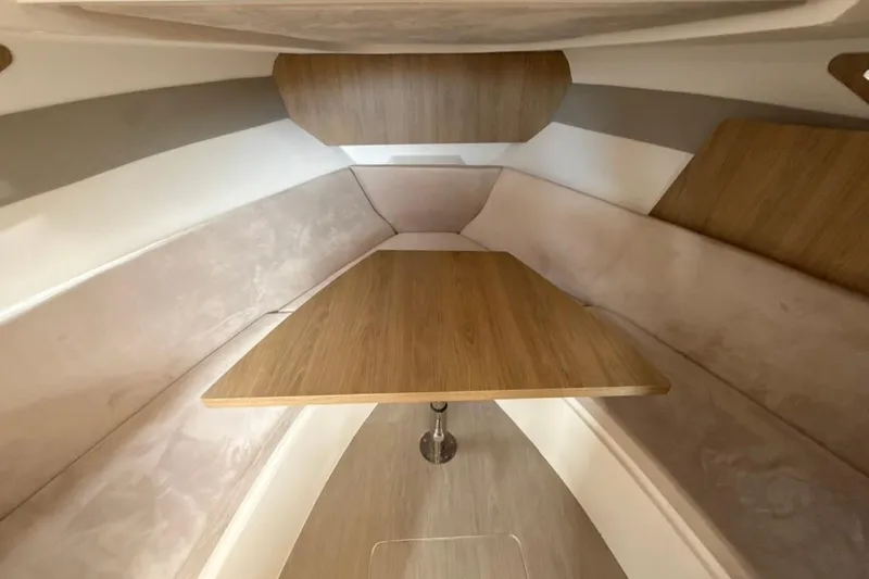 Slide: The Image of Interior of 2025 NX Boats 340 Sport Coupe, featuring a sleek wooden table and cushioned seating. - 69