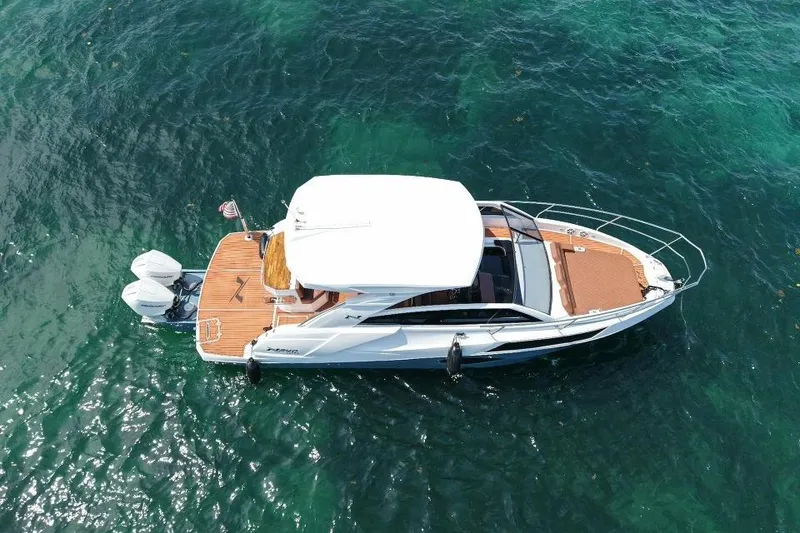 Slide: The Image of 2025 NX Boats 340 Sport Coupe cruising on clear blue water. - 7