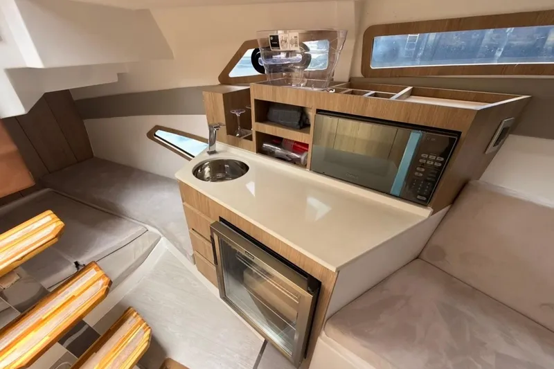 Slide: The Image of Interior of 2025 NX Boats 340 Sport Coupe featuring kitchenette with microwave and sink. - 71