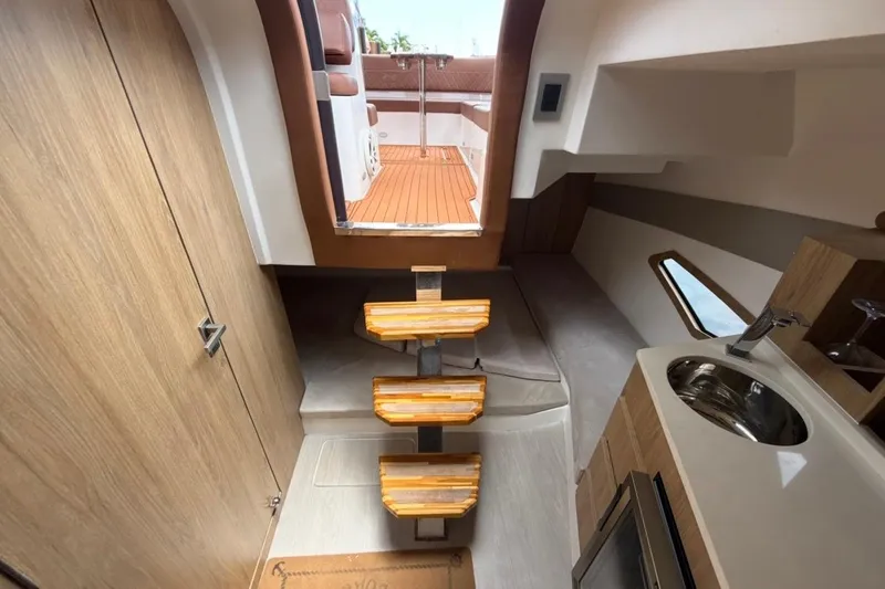 Slide: The Image of Interior of 2025 NX Boats 340 Sport Coupe with wooden stairs and kitchenette. - 72