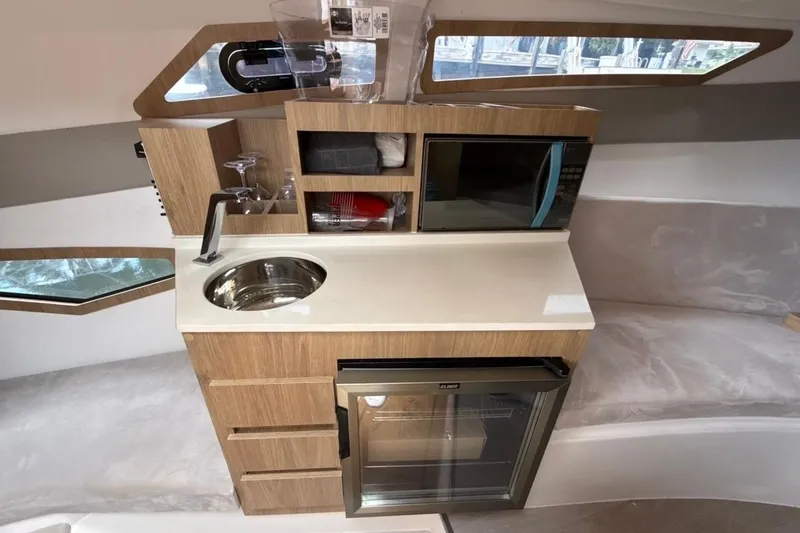Slide: The Image of Modern kitchenette in 2025 NX Boats 340 Sport Coupe with sink, microwave, and storage. - 73