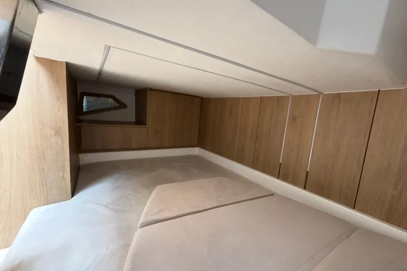 Slide: The Image of Interior cabin of 2025 NX Boats 340 Sport Coupe with wood paneling and cozy bedding. - 74