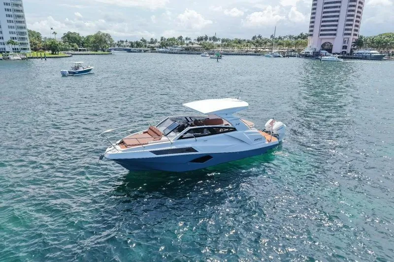 Slide: The Image of 2025 NX Boats 340 Sport Coupe cruising on a sunny day in a scenic harbor. - 8