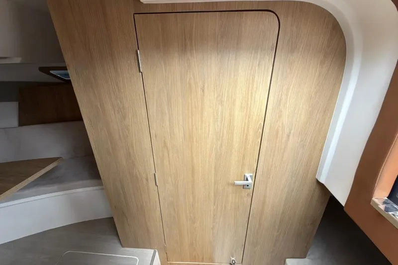 Slide: The Image of Interior of 2025 NX Boats 340 Sport Coupe featuring a wooden cabin door. - 81