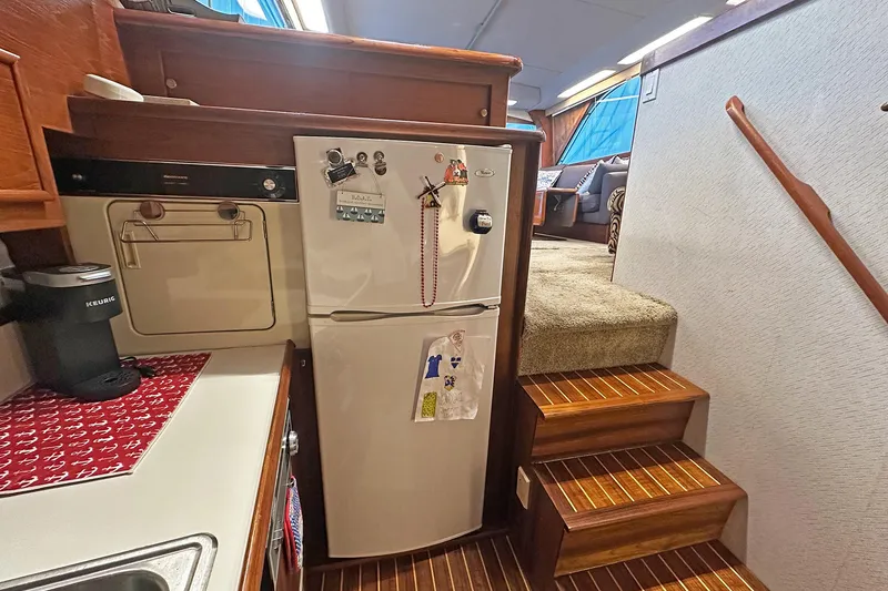 Slide: The Image of 1988 Ocean Yachts 48 Super Sport interior with kitchen and stairs, featuring a refrigerator and coffee maker. - 20