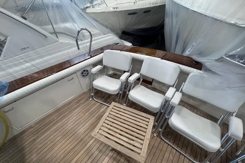 Slide: The Image of 1988 Ocean Yachts 48 Super Sport deck with white chairs and wooden table. - 36