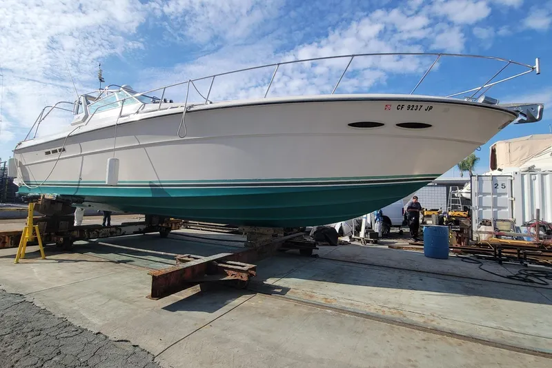 Slide: The Image of 1987 Sea Ray 390 Express yacht on dry dock under a clear blue sky. - 22