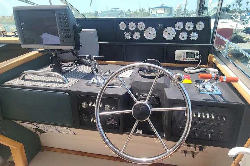 Slide: The Image of 1987 Sea Ray 390 Express helm with steering wheel, gauges, and navigation equipment. - 9