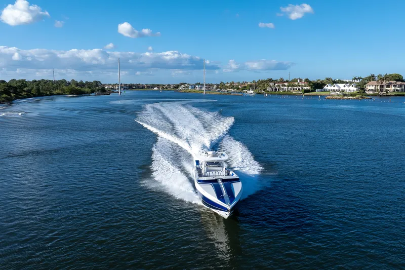 Slide: The Image of A 2018 Hann 53 boat cruising on a scenic waterway under a clear blue sky. - 23