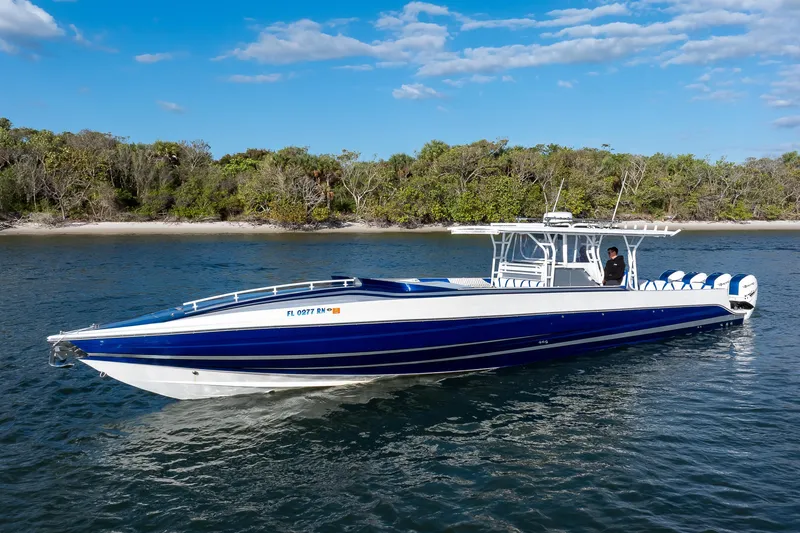 Slide: The Image of 2018 Hann 53 boat on water, blue and white design, near lush shoreline. - 27