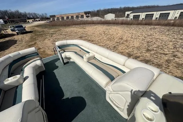 Slide: The Image of 2002 Bennington 2575RL I/O pontoon boat with spacious seating and cup holders, parked outdoors. - 20