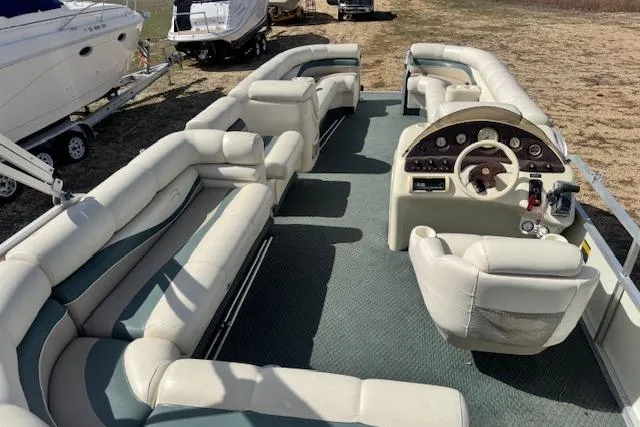 Slide: The Image of 2002 Bennington 2575RL I/O pontoon boat with spacious seating and helm, parked outdoors. - 8