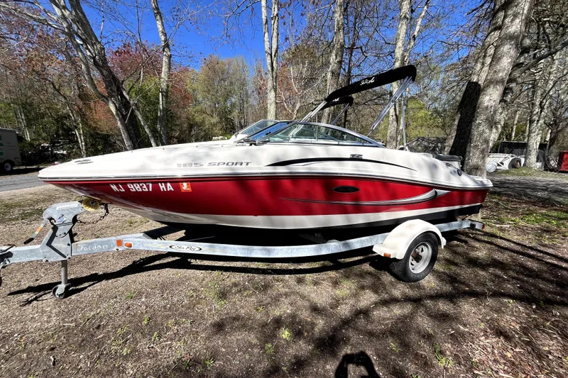 The Image of 2008 Sea Ray 185 Sport boat on trailer in wooded area. - 0