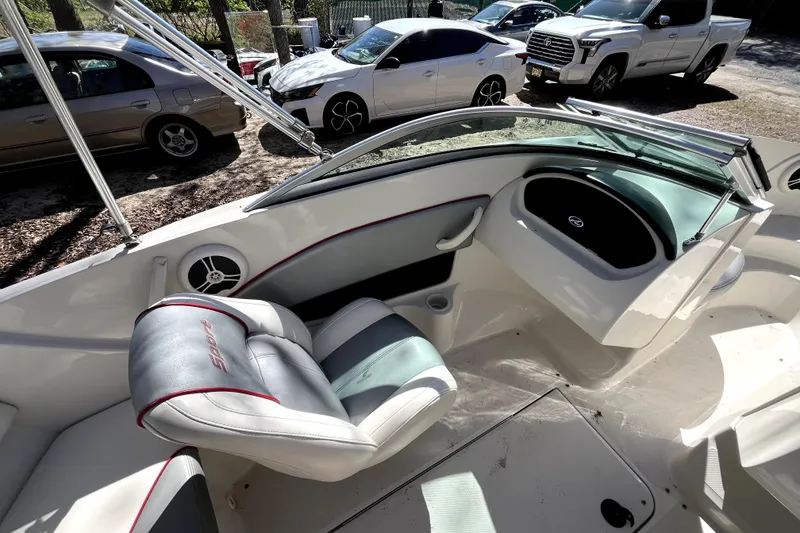 Slide: The Image of 2008 Sea Ray 185 Sport boat interior with seating and dashboard, parked near cars. - 10