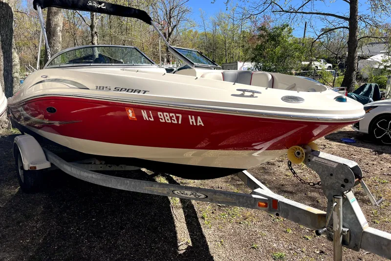 Slide: The Image of 2008 Sea Ray 185 Sport boat on trailer, red and white exterior, parked outdoors. - 2