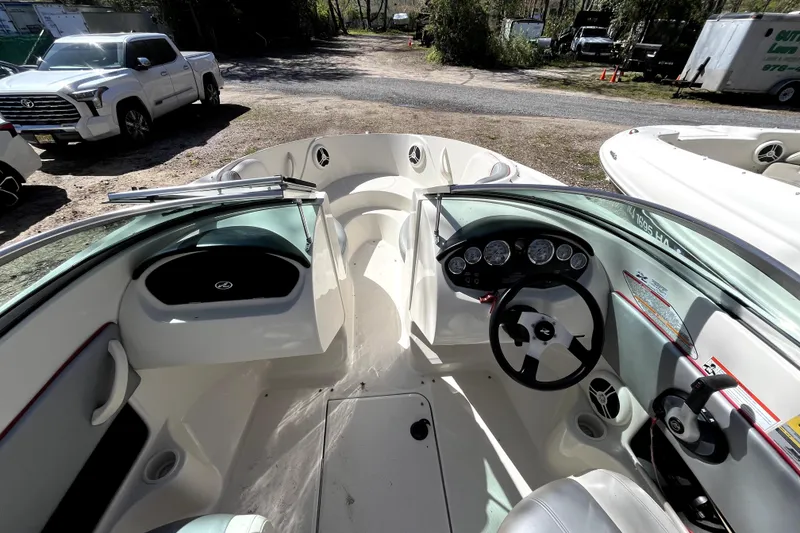 Slide: The Image of 2008 Sea Ray 185 Sport boat interior with steering wheel and dashboard, parked outdoors. - 7