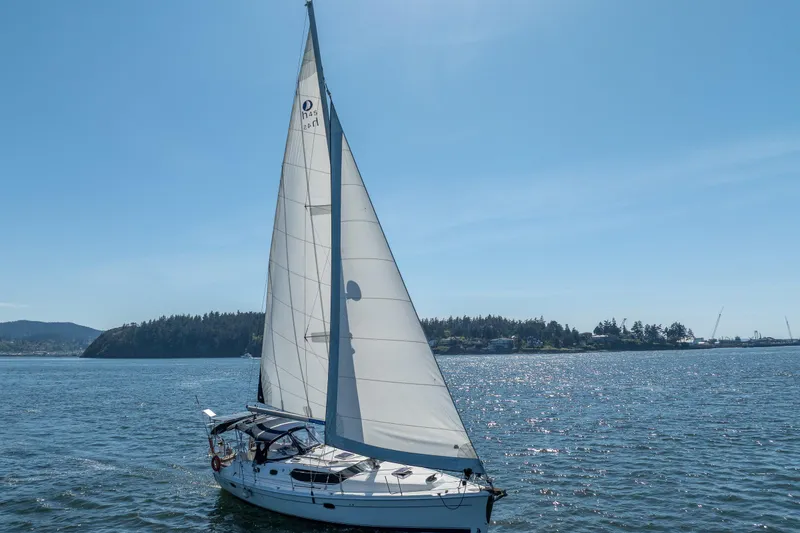 Slide: The Image of 2008 Hunter 45 Deck Salon sailing on a sunny day near a forested shoreline. - 5
