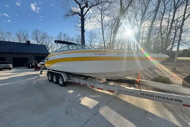 Slide: The Image of 2003 Crownline 270 BR boat on trailer, parked outdoors with sunlight filtering through trees. - 3