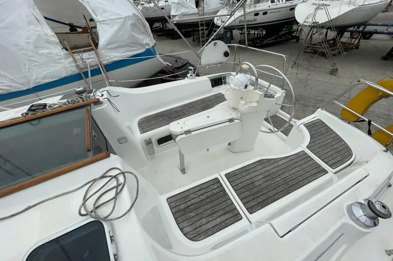 Slide: The Image of 2002 Beneteau 331 sailboat cockpit with wooden seating and steering wheel in a marina. - 13