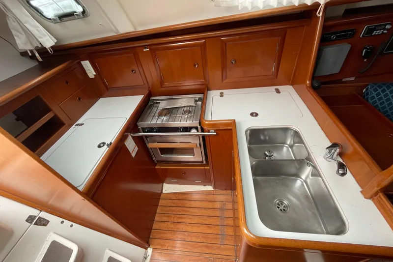 Slide: The Image of 2002 Beneteau 331 yacht kitchen with stove, sink, and wooden cabinetry. - 16
