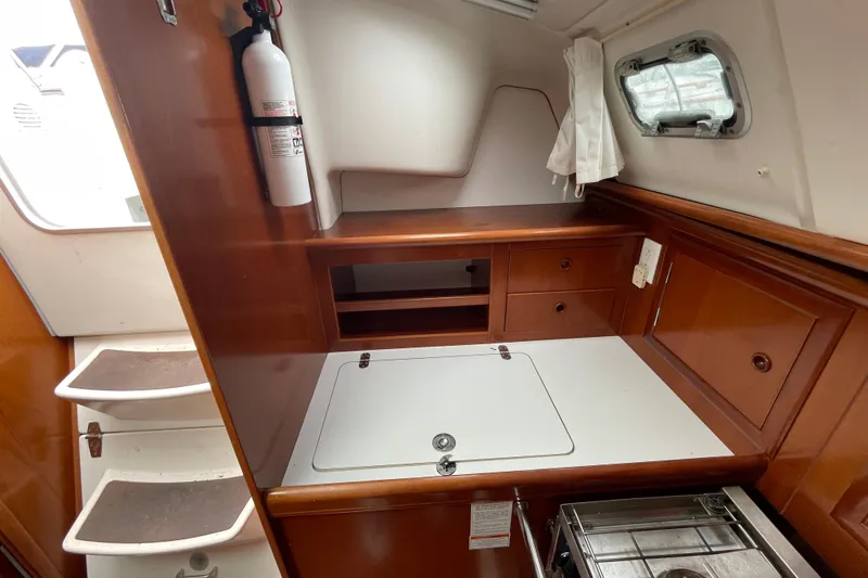 Slide: The Image of Interior of 2002 Beneteau 331 sailboat with wooden cabinetry and compact kitchen area. - 17