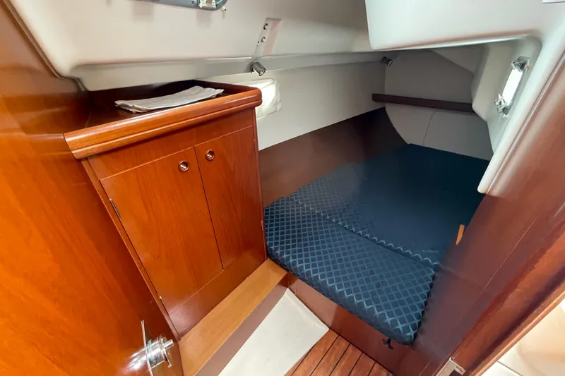 Slide: The Image of Cozy cabin interior of 2002 Beneteau 331 sailboat with wooden cabinetry and cushioned berth. - 18