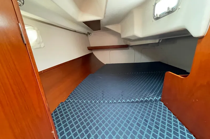 Slide: The Image of Interior cabin of 2002 Beneteau 331 sailboat, featuring wooden finish and blue patterned bedding. - 19