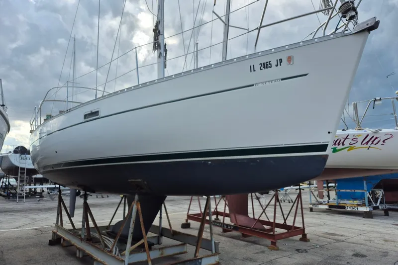 Slide: The Image of 2002 Beneteau 331 sailboat on dry dock, ready for maintenance under cloudy skies. - 2