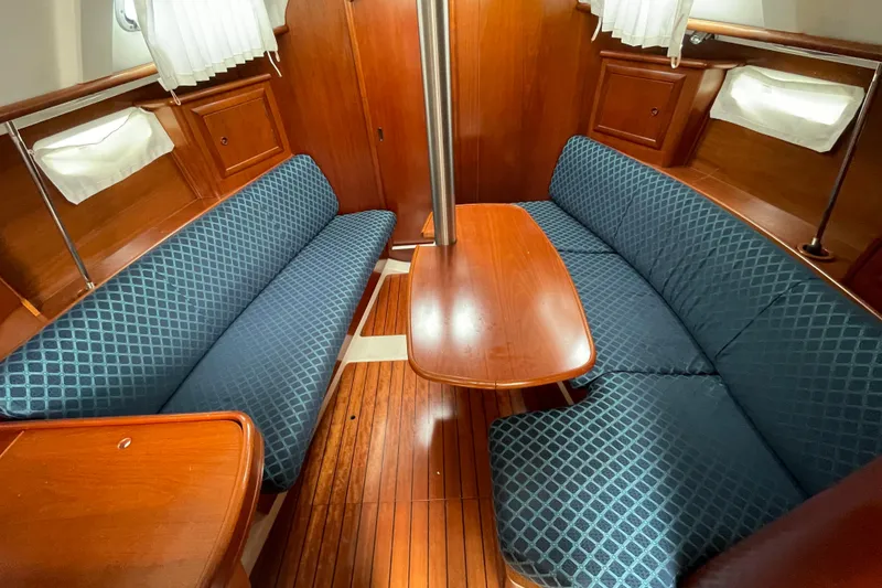 Slide: The Image of Interior of 2002 Beneteau 331 sailboat with wooden table and blue cushioned seating. - 21