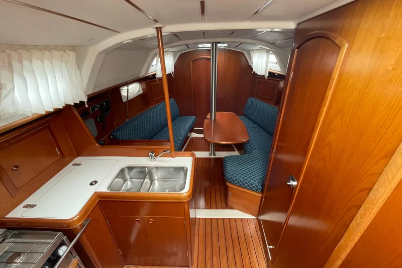 Slide: The Image of Interior of 2002 Beneteau 331 sailboat with wooden table and blue cushioned seating. - 28