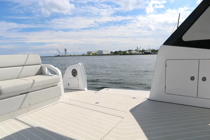 Slide: The Image of 2023 Azimut Verve 47 yacht deck with seating, overlooking calm waters and distant shoreline. - 18
