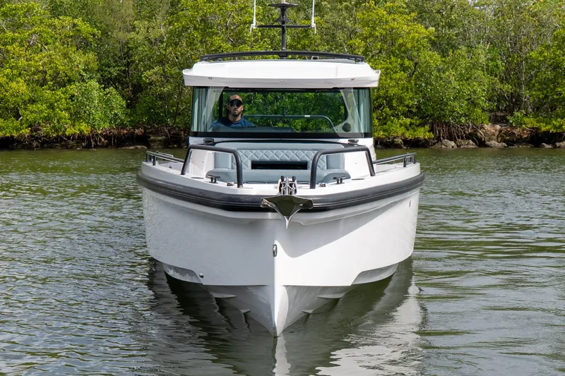Slide: The Image of 2022 Axopar 37 XC Cross Cabin boat navigating through calm waters, surrounded by lush greenery. - 10