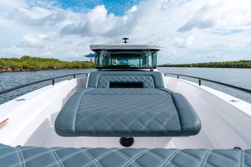 Slide: The Image of 2022 Axopar 37 XC Cross Cabin boat with cushioned seating on a calm waterway. - 17