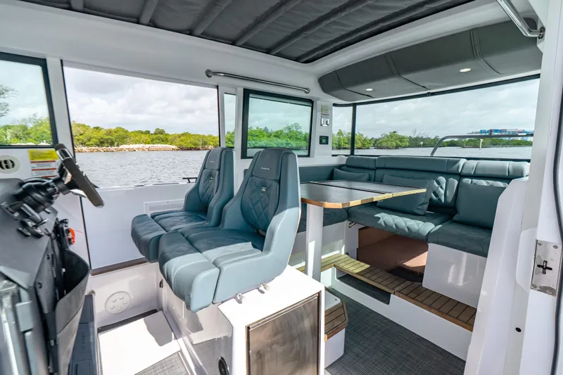 Slide: The Image of 2022 Axopar 37 XC Cross Cabin interior with seating and table, overlooking water. - 29